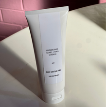 Load image into Gallery viewer, A 100ml bottle of lightweight hydrating hand and nail cream infused with a sensual fragrance inspired by Baccarat Rouge. Contains purified water, avocado oil, jojoba oil, macadamia oil, shea butter, cocoa butter, and aloe vera leaf juice powder. Suitable for daily use.